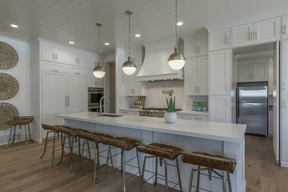 Modern inredning av ett mellanstort kök, med en undermonterad diskho, skåp i shakerstil, vita skåp, bänkskiva i kvarts, vitt stänkskydd, stänkskydd i glaskakel, rostfria vitvaror, ljust trägolv, en köksö och beiget golv