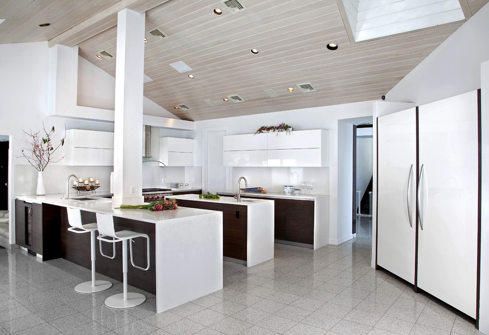 Photo of a modern kitchen/diner in New York with a submerged sink, flat-panel cabinets, quartz worktops, white splashback, integrated appliances and multiple islands.