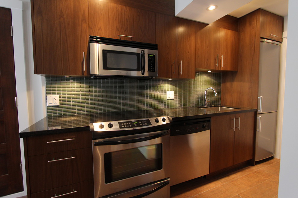 Example of a small minimalist single-wall medium tone wood floor eat-in kitchen design in Vancouver with an undermount sink, flat-panel cabinets, dark wood cabinets, granite countertops, green backsplash, glass tile backsplash, stainless steel appliances and no island