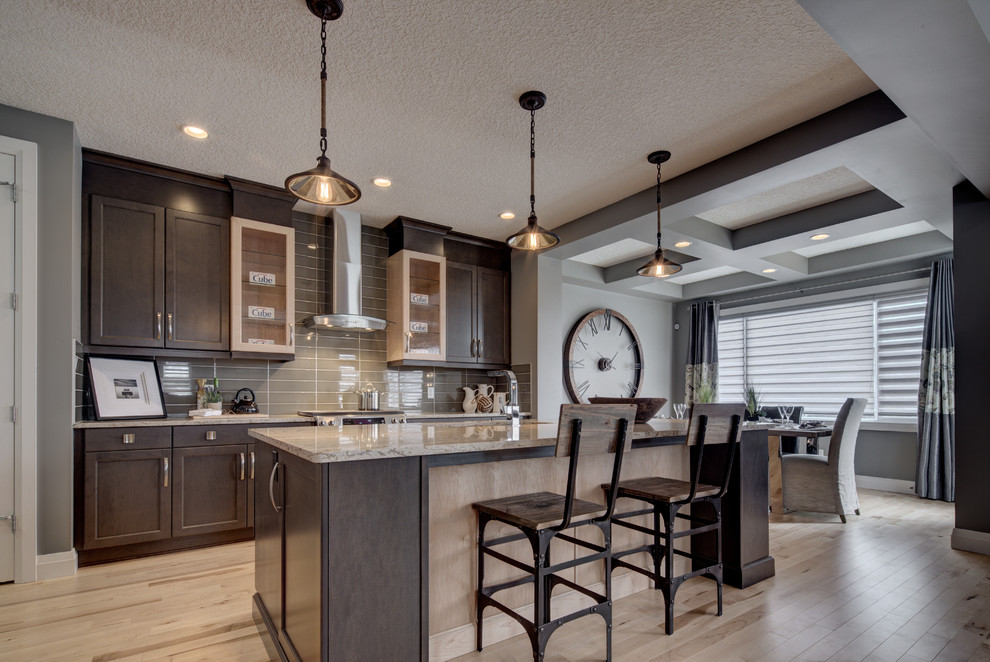 Open concept kitchen - mid-sized eclectic l-shaped light wood floor and beige floor open concept kitchen idea in Calgary with an undermount sink, recessed-panel cabinets, dark wood cabinets, quartz countertops, gray backsplash, glass tile backsplash, stainless steel appliances, an island and gray countertops