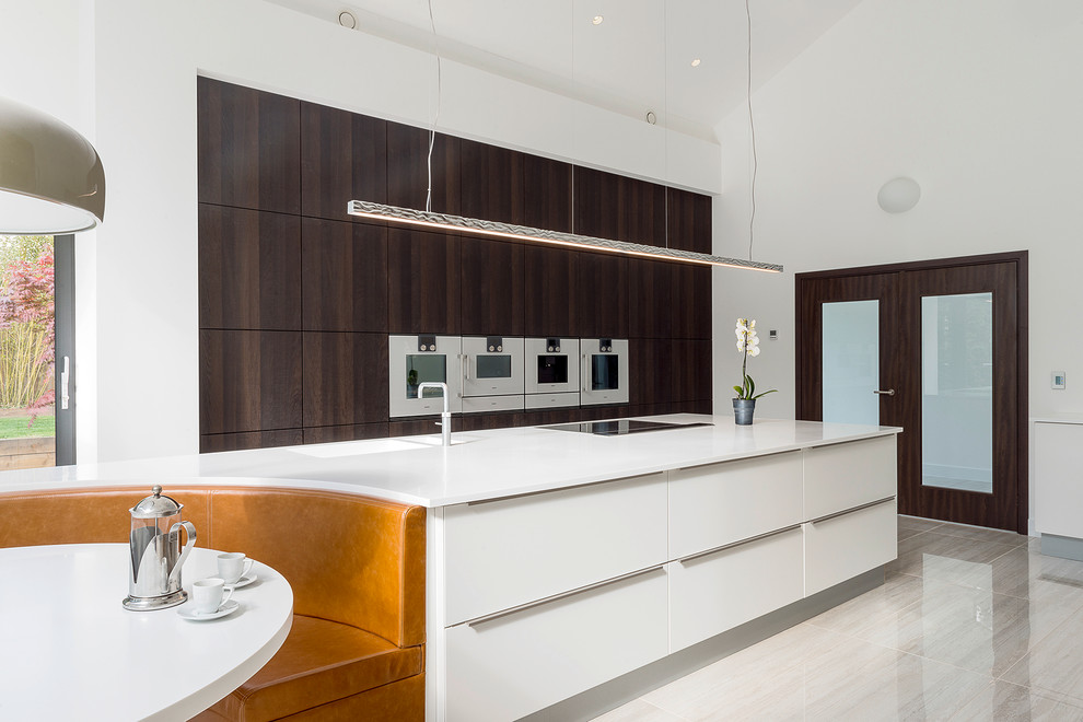 Photo of an expansive contemporary galley kitchen in Other with flat-panel cabinets, an island, white cabinets and stainless steel appliances.