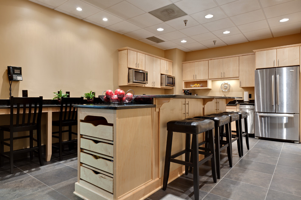 Eat-in kitchen - large contemporary l-shaped porcelain tile and gray floor eat-in kitchen idea in Atlanta with stainless steel appliances, flat-panel cabinets, light wood cabinets, an undermount sink, granite countertops, black backsplash, an island, granite backsplash and black countertops