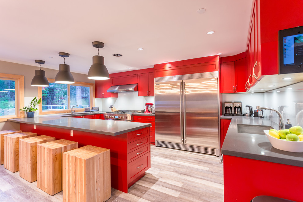 Foto på ett stort funkis grå kök, med en undermonterad diskho, skåp i shakerstil, röda skåp, granitbänkskiva, vitt stänkskydd, glaspanel som stänkskydd, rostfria vitvaror, vinylgolv, en köksö och grått golv