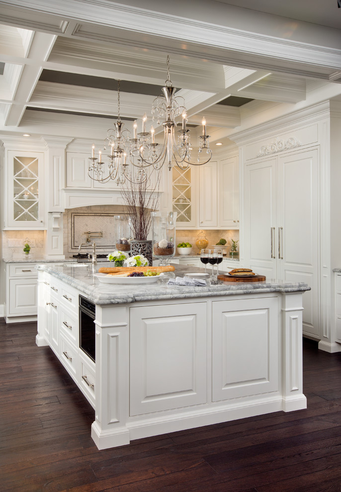 Large elegant galley medium tone wood floor enclosed kitchen photo in Columbus with a farmhouse sink, recessed-panel cabinets, white cabinets, granite countertops, multicolored backsplash, white appliances and an island