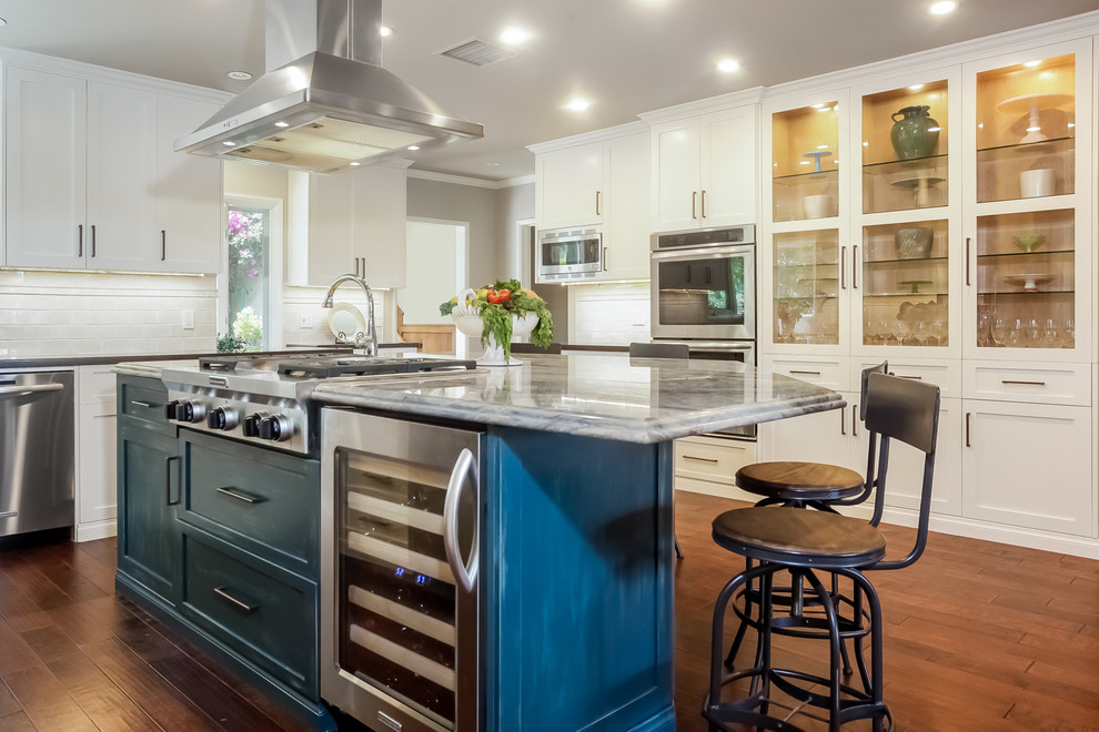 Transitional medium tone wood floor open concept kitchen photo in Los Angeles with shaker cabinets, white cabinets, solid surface countertops, white backsplash, subway tile backsplash, stainless steel appliances, an island and a single-bowl sink