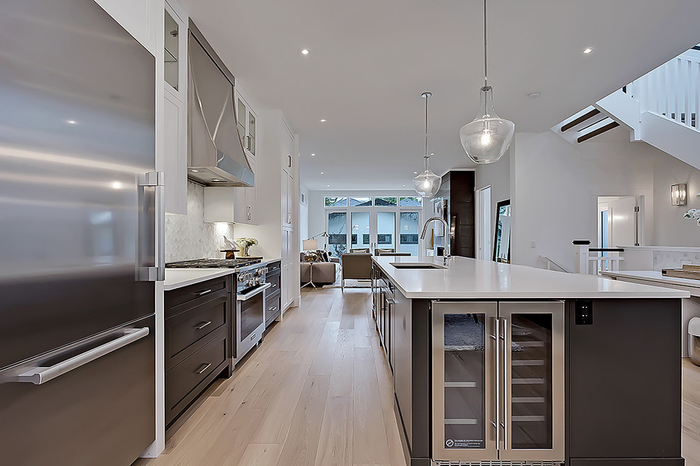 This is an example of a scandinavian galley kitchen in Calgary with a submerged sink, shaker cabinets, stainless steel appliances and an island.