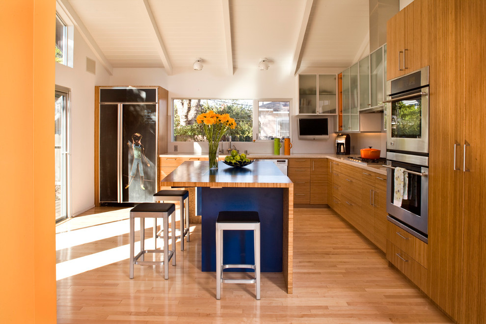 Ejemplo de cocina contemporánea con armarios con paneles lisos, puertas de armario de madera oscura, electrodomésticos de acero inoxidable, suelo de madera en tonos medios y una isla