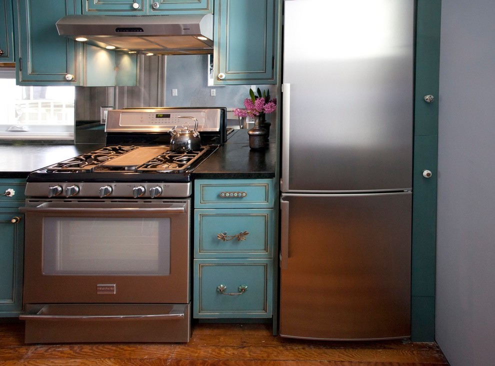 Example of a trendy kitchen design in New York with recessed-panel cabinets, blue cabinets, soapstone countertops, mirror backsplash and stainless steel appliances