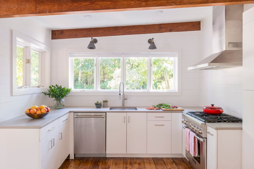 Photo of a farmhouse u-shaped kitchen in Boston with a submerged sink, flat-panel cabinets, white cabinets, stainless steel appliances, medium hardwood flooring, no island and brown floors.