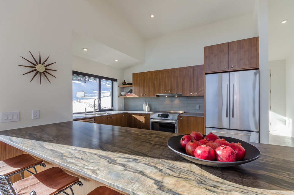 Photo of a large modern u-shaped enclosed kitchen in San Francisco with a submerged sink, flat-panel cabinets, light wood cabinets, composite countertops, grey splashback, ceramic splashback, stainless steel appliances, a breakfast bar, travertine flooring and beige floors.