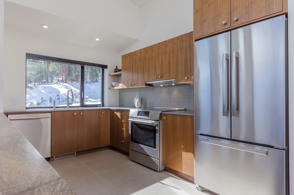 Photo of a large modern u-shaped enclosed kitchen in San Francisco with a submerged sink, flat-panel cabinets, light wood cabinets, composite countertops, grey splashback, ceramic splashback, stainless steel appliances, travertine flooring, a breakfast bar and beige floors.