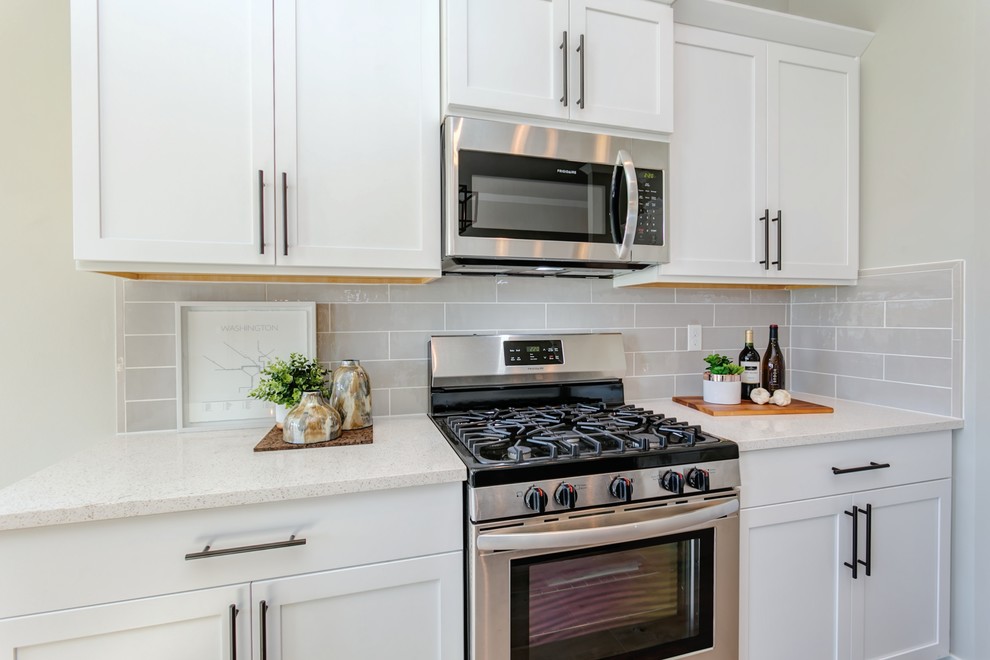 Example of a small transitional l-shaped laminate floor and gray floor open concept kitchen design in Seattle with an undermount sink, shaker cabinets, dark wood cabinets, quartz countertops, gray backsplash, porcelain backsplash, stainless steel appliances, an island and white countertops