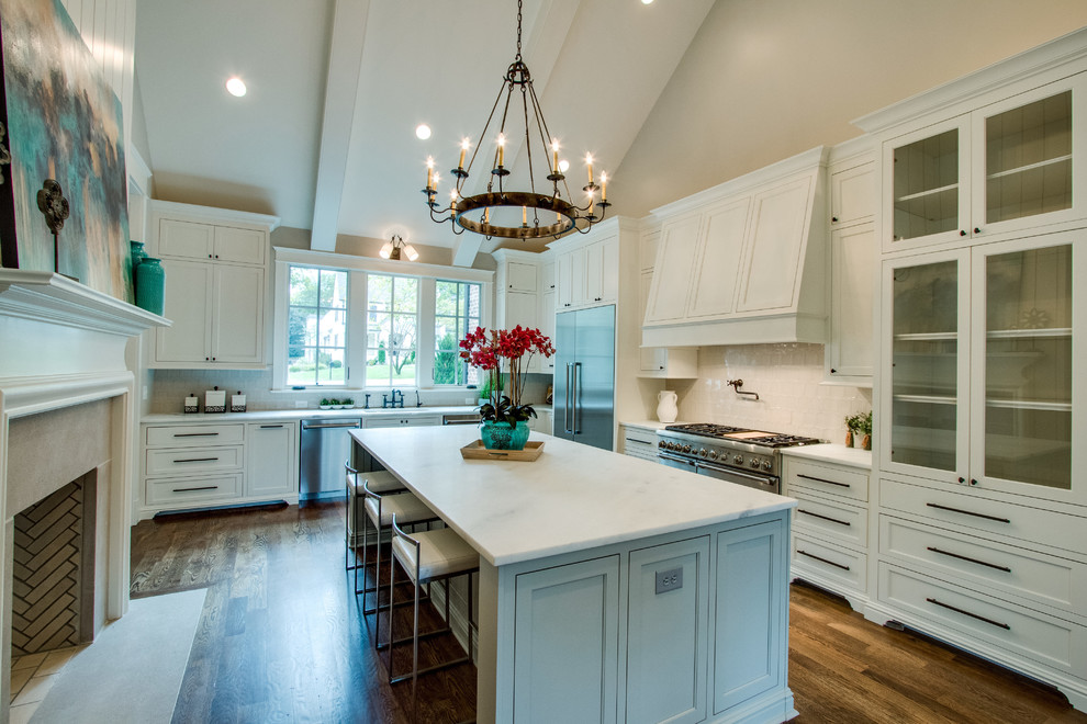 This is an example of a large traditional l-shaped enclosed kitchen in Nashville with a submerged sink, shaker cabinets, white cabinets, marble worktops, grey splashback, ceramic splashback, stainless steel appliances, an island and medium hardwood flooring.