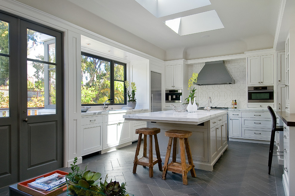 Imagen de cocina clásica renovada cerrada con armarios con paneles empotrados, puertas de armario blancas, encimera de mármol, salpicadero blanco, electrodomésticos de acero inoxidable y suelo gris