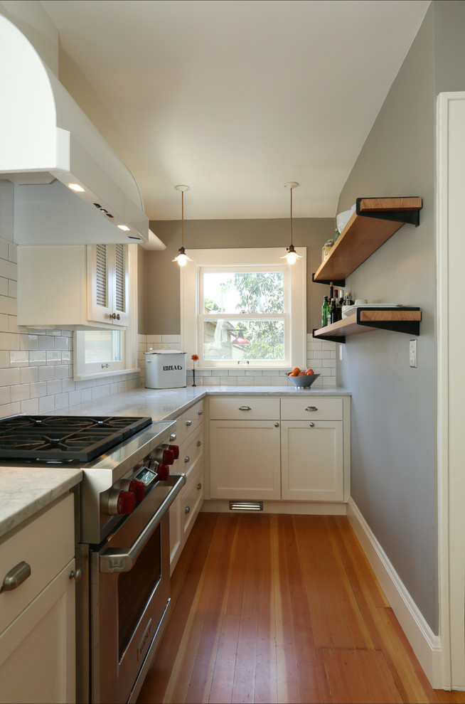 Inspiration for a country l-shaped enclosed kitchen remodel in Portland with a farmhouse sink, shaker cabinets, white cabinets, marble countertops, white backsplash, subway tile backsplash and stainless steel appliances