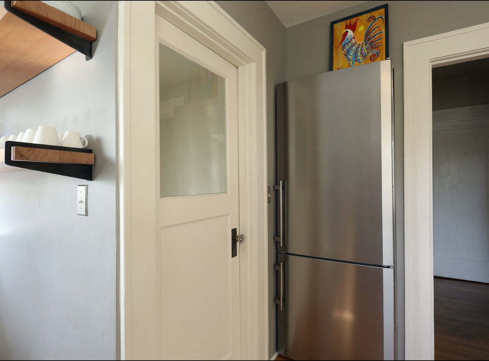 ポートランドにあるお手頃価格の小さなエクレクティックスタイルのおしゃれなキッチン (落し込みパネル扉のキャビネット、白いキャビネット、シルバーの調理設備、アイランドなし) の写真