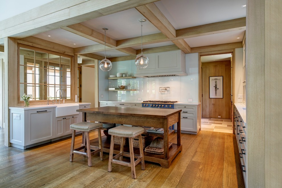 Example of a mid-sized beach style u-shaped medium tone wood floor and brown floor open concept kitchen design in New York with a farmhouse sink, shaker cabinets, gray cabinets, white backsplash, glass sheet backsplash, an island, quartz countertops and colored appliances
