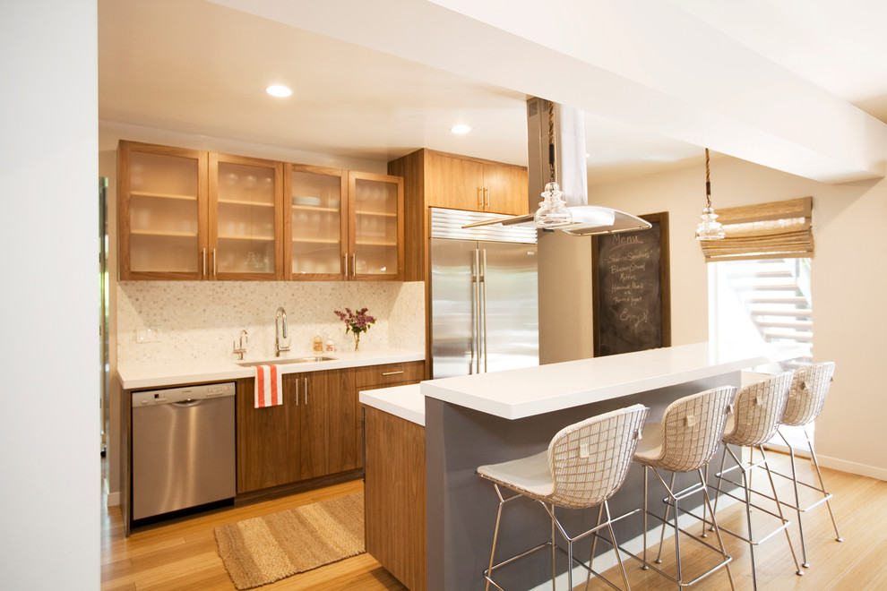 Cette image montre une cuisine design avec une crédence en mosaïque et un électroménager en acier inoxydable.