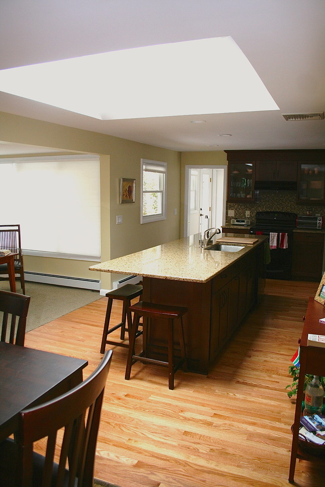 Foto på ett mellanstort vintage kök, med luckor med infälld panel, granitbänkskiva, flerfärgad stänkskydd, svarta vitvaror, ljust trägolv, en nedsänkt diskho och skåp i mörkt trä