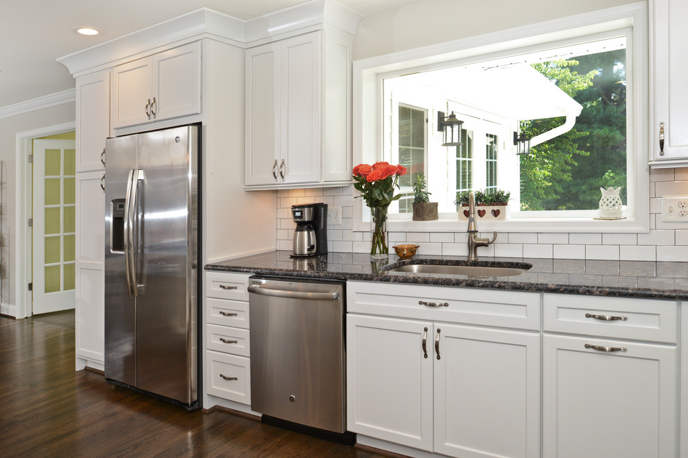 Immagine di una cucina moderna di medie dimensioni con ante lisce, ante bianche, top in zinco, paraspruzzi bianco, elettrodomestici in acciaio inossidabile, pavimento marrone e top nero
