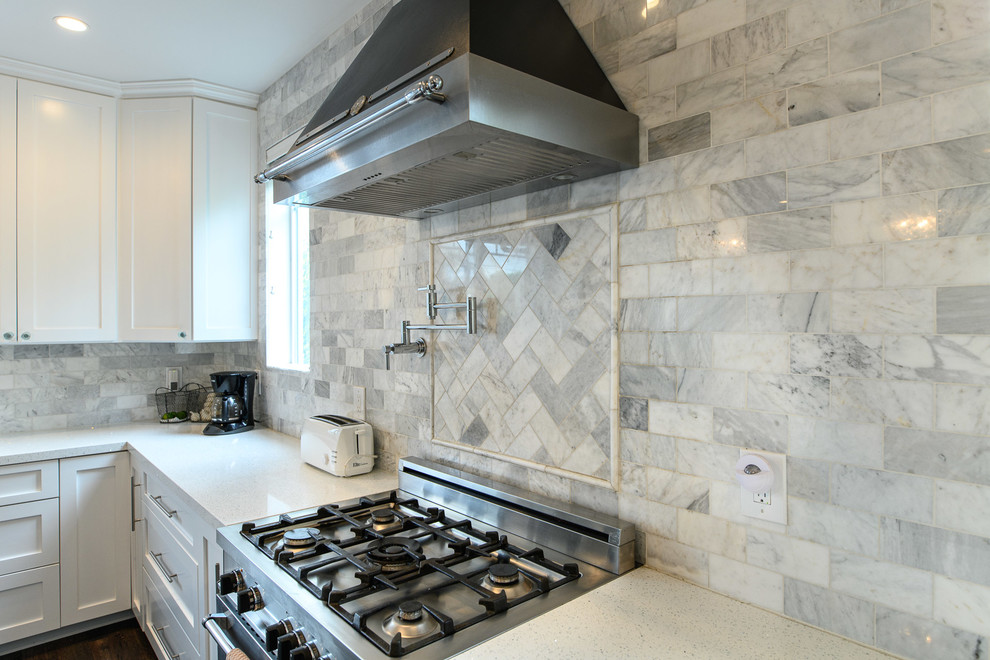 Foto på ett stort funkis vit kök, med skåp i shakerstil, vita skåp, bänkskiva i kvarts, grått stänkskydd, rostfria vitvaror och en köksö