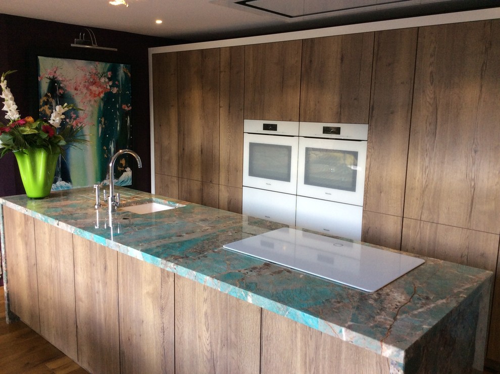 Aménagement d'une cuisine ouverte contemporaine en bois brun avec un placard à porte plane, un électroménager blanc, un sol en bois brun, îlot, un sol marron et un plan de travail vert.