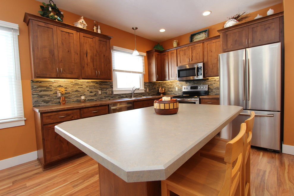 Mid-sized elegant l-shaped light wood floor eat-in kitchen photo in Grand Rapids with a double-bowl sink, recessed-panel cabinets, medium tone wood cabinets, laminate countertops, multicolored backsplash, matchstick tile backsplash, stainless steel appliances and an island