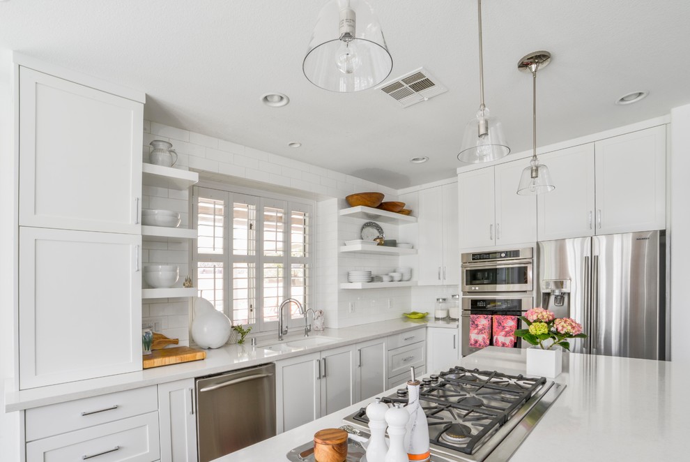 Mid-sized transitional l-shaped kitchen photo in Las Vegas with an undermount sink, shaker cabinets, white cabinets, white backsplash, subway tile backsplash, stainless steel appliances, an island and quartz countertops