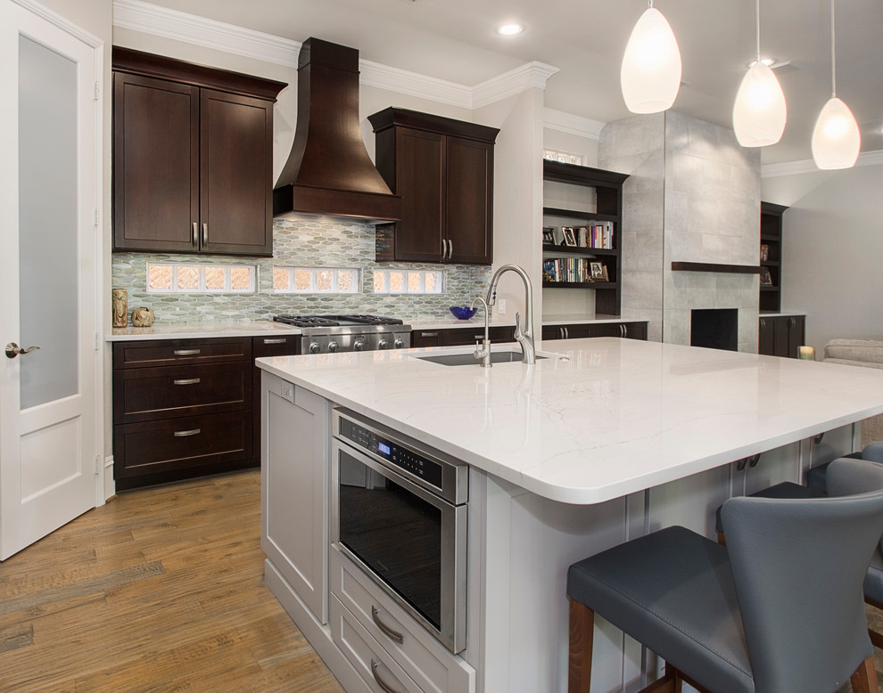 Large transitional l-shaped light wood floor open concept kitchen photo in Dallas with an undermount sink, shaker cabinets, dark wood cabinets, quartz countertops, metallic backsplash, mosaic tile backsplash, stainless steel appliances and an island