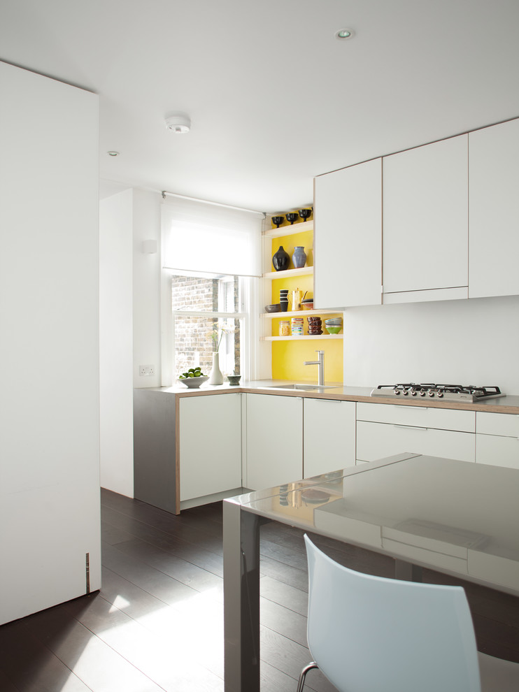 Exempel på ett mellanstort modernt kök, med en enkel diskho, släta luckor, vita skåp, laminatbänkskiva, gult stänkskydd, rostfria vitvaror och mörkt trägolv
