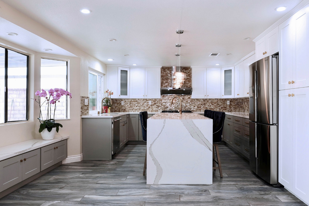 Inspiration for a large world-inspired u-shaped kitchen in Los Angeles with a built-in sink, shaker cabinets, white cabinets, laminate countertops, multi-coloured splashback, glass sheet splashback, stainless steel appliances, medium hardwood flooring, an island and grey floors.