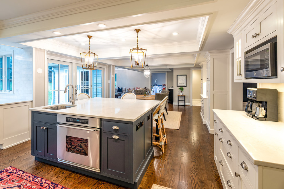 Example of a large transitional u-shaped dark wood floor and brown floor eat-in kitchen design in Philadelphia with a farmhouse sink, shaker cabinets, white cabinets, quartzite countertops, white backsplash, marble backsplash, paneled appliances, an island and white countertops