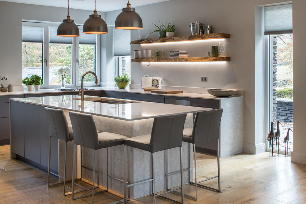 Photo of a modern l-shaped kitchen in Other with a submerged sink, flat-panel cabinets, grey cabinets, light hardwood flooring, an island, beige floors and white worktops.