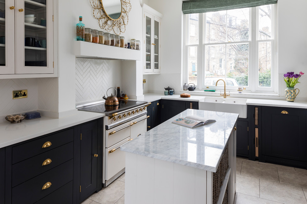 Elegant galley beige floor eat-in kitchen photo in London with a double-bowl sink, shaker cabinets, black cabinets, marble countertops, white backsplash, black appliances and an island