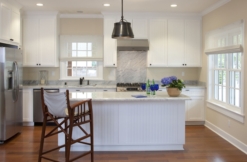 Example of a beach style l-shaped kitchen design in San Diego with flat-panel cabinets, white cabinets, white backsplash, stone slab backsplash and stainless steel appliances