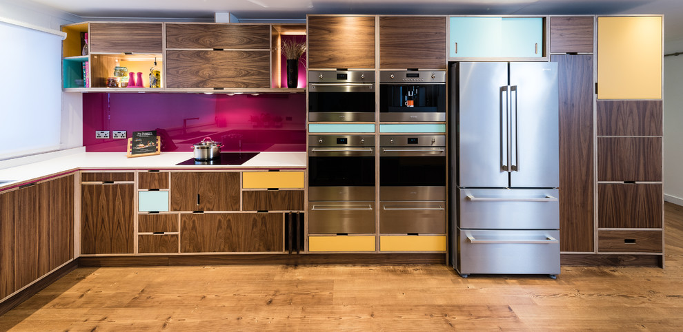 Immagine di una cucina minimalista con ante lisce, ante in legno scuro, paraspruzzi rosa, elettrodomestici in acciaio inossidabile, pavimento in legno massello medio, nessuna isola e pavimento marrone