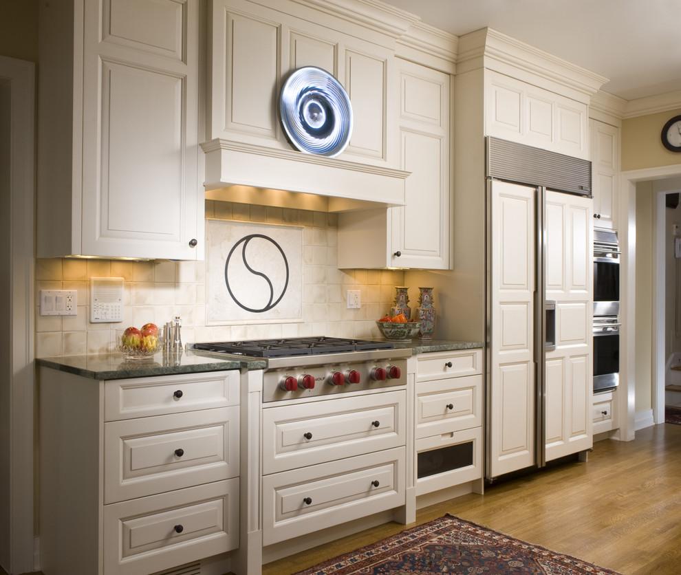 Ejemplo de cocina tradicional de obra con electrodomésticos de acero inoxidable, puertas de armario blancas, encimera de granito, salpicadero beige y salpicadero de azulejos de cerámica