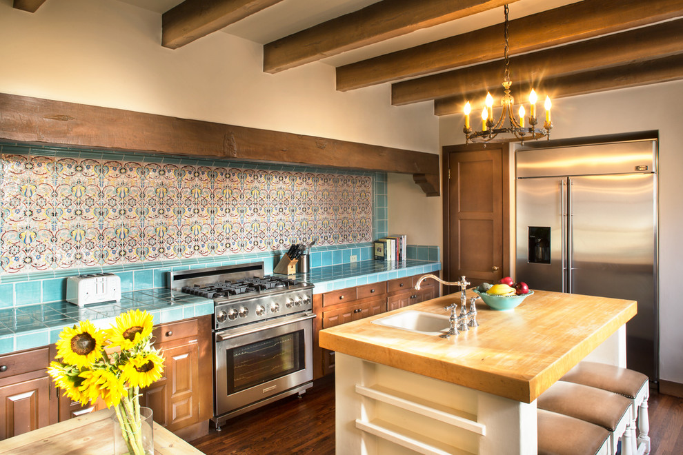 Küche mit profilierten Schrankfronten, dunklen Holzschränken, Küchenrückwand in Blau, Küchengeräten aus Edelstahl, dunklem Holzboden und Einbauwaschbecken in Santa Barbara