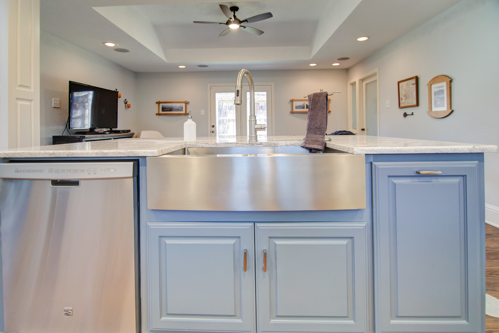Foto på ett mellanstort lantligt vit linjärt kök med öppen planlösning, med en rustik diskho, luckor med upphöjd panel, vita skåp, granitbänkskiva, flerfärgad stänkskydd, stänkskydd i stickkakel, rostfria vitvaror, mellanmörkt trägolv, en köksö och brunt golv