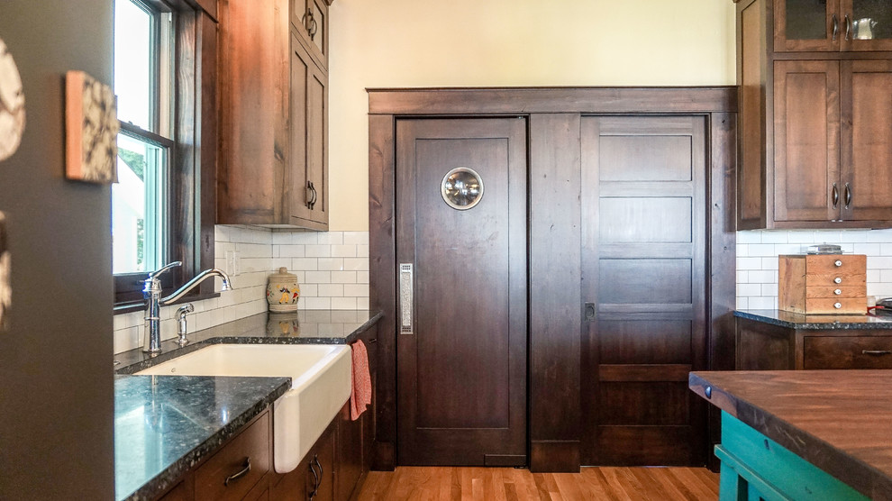 Eat-in kitchen - mid-sized craftsman l-shaped medium tone wood floor eat-in kitchen idea in Boise with a farmhouse sink, recessed-panel cabinets, green cabinets, wood countertops, white backsplash, porcelain backsplash and an island