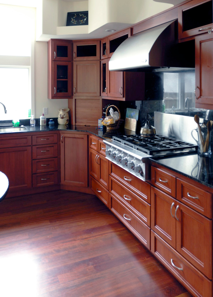 Foto på ett mellanstort funkis svart kök, med en undermonterad diskho, luckor med infälld panel, skåp i mörkt trä, granitbänkskiva, svart stänkskydd, rostfria vitvaror, mörkt trägolv, en köksö och brunt golv