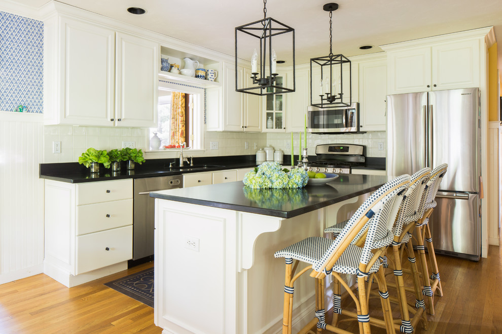 Example of a mid-sized transitional single-wall light wood floor eat-in kitchen design in Boston with an undermount sink, recessed-panel cabinets, white cabinets, granite countertops, white backsplash, ceramic backsplash, stainless steel appliances and an island