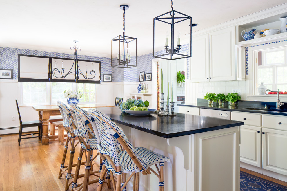 Eat-in kitchen - mid-sized cottage light wood floor eat-in kitchen idea in Boston with an undermount sink, white backsplash, porcelain backsplash, an island, raised-panel cabinets, white cabinets, granite countertops and stainless steel appliances