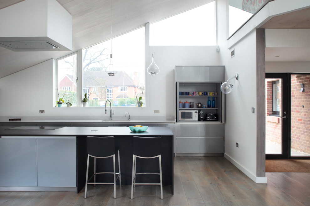 Inspiration for a contemporary galley kitchen in Buckinghamshire with flat-panel cabinets, grey cabinets, dark hardwood flooring, an island, brown floors and white worktops.