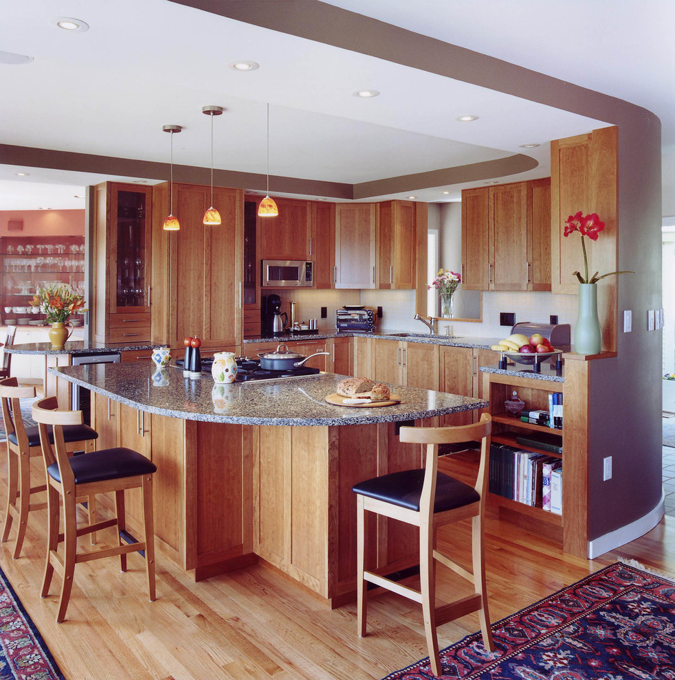 Klassische Küche in U-Form mit Unterbauwaschbecken, Schrankfronten im Shaker-Stil, hellen Holzschränken, Küchenrückwand in Weiß, Rückwand aus Porzellanfliesen, Küchengeräten aus Edelstahl, hellem Holzboden und Kücheninsel in Boston