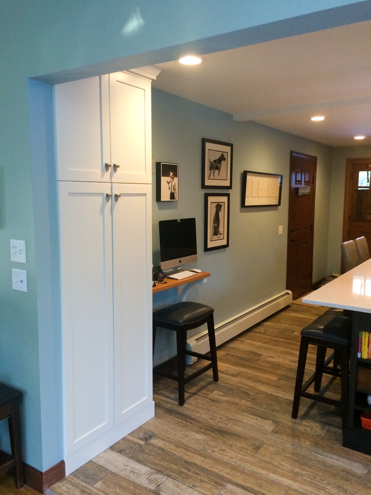 Small trendy single-wall medium tone wood floor kitchen photo in Boston with an undermount sink, recessed-panel cabinets, white cabinets, granite countertops, white backsplash, subway tile backsplash, stainless steel appliances and an island