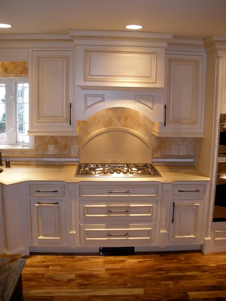 This is an example of a medium sized traditional single-wall kitchen/diner in Cleveland with beaded cabinets, white cabinets, engineered stone countertops, beige splashback, stainless steel appliances, medium hardwood flooring and an island.