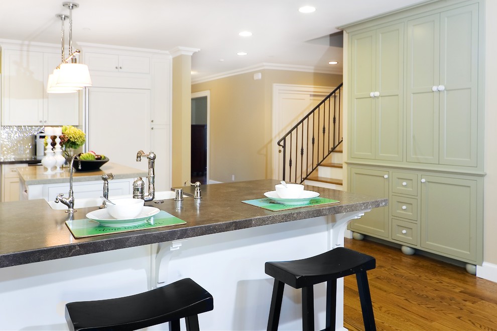 Diseño de cocina actual con puertas de armario verdes, fregadero sobremueble, electrodomésticos con paneles y salpicadero blanco