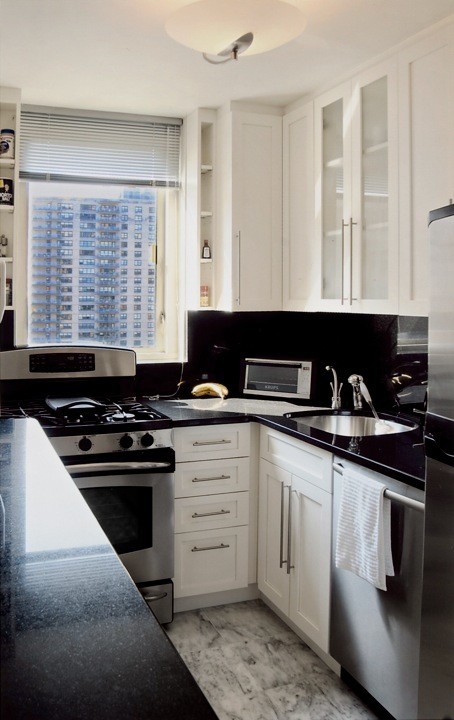 Klassisk inredning av ett avskilt, litet u-kök, med en undermonterad diskho, skåp i shakerstil, vita skåp, bänkskiva i koppar, svart stänkskydd, stänkskydd i sten, rostfria vitvaror, marmorgolv och grått golv