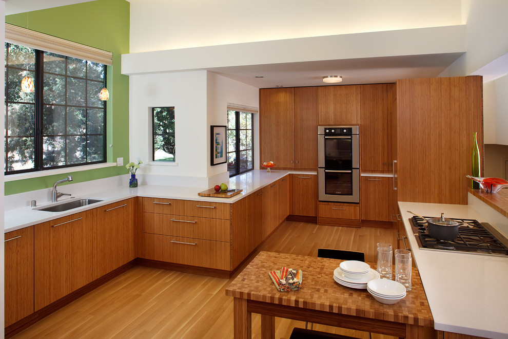 Пример оригинального дизайна: отдельная, прямая кухня среднего размера в современном стиле с техникой из нержавеющей стали, врезной мойкой, плоскими фасадами, фасадами цвета дерева среднего тона, светлым паркетным полом и окном без острова